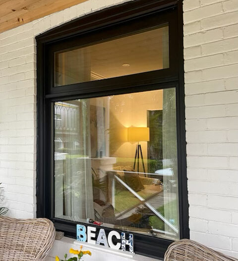 Black vinyl awning window installed above a large direct set picture window on a residential home, creating a modern stacked window design.