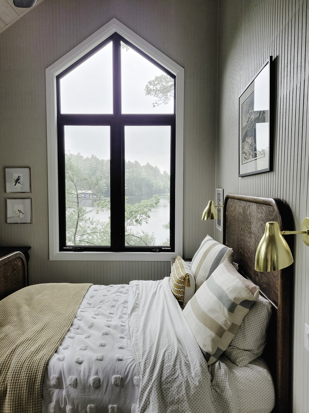 Bedroom in a Muskoka cottage with black vinyl casement windows and custom direct set peak windows.