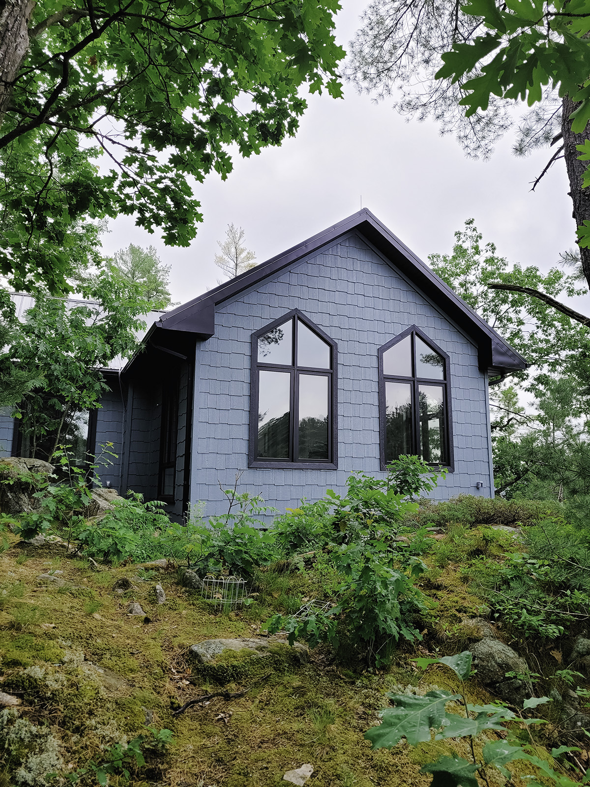 Black vinyl casement and direct set peak windows installed on a Muskoka cottage exterior.