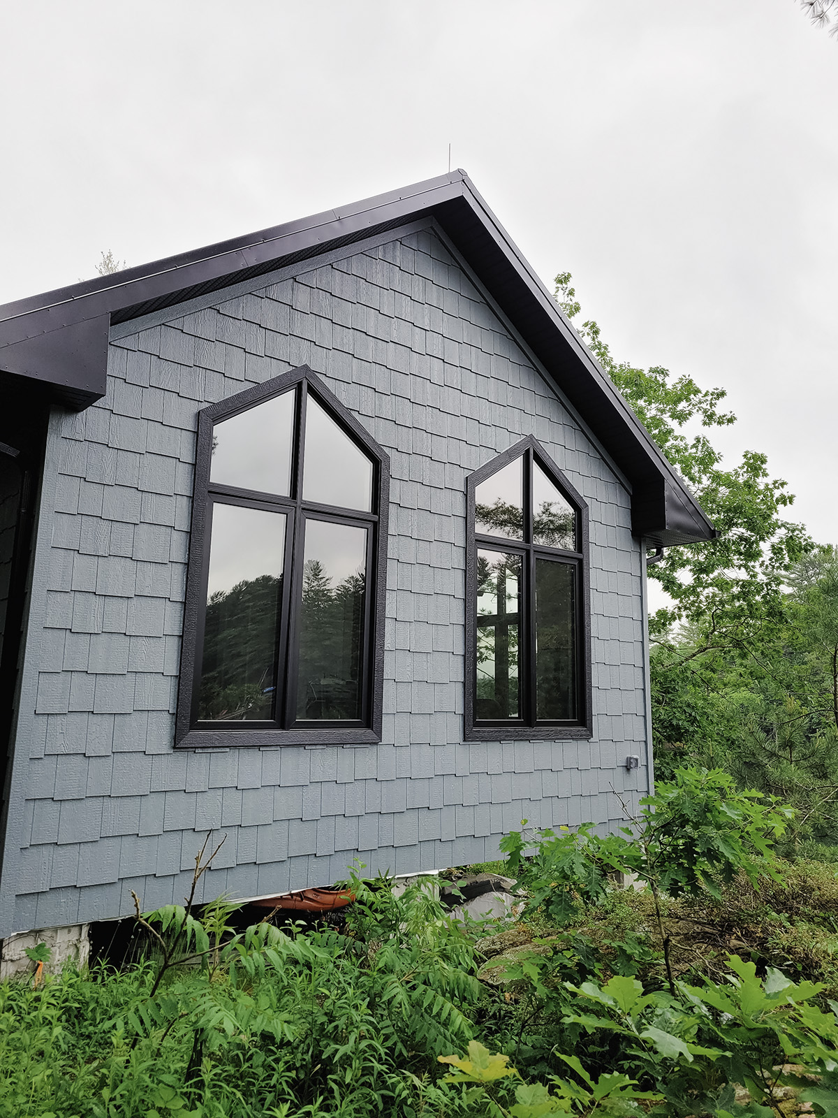 Muskoka cottage exterior featuring black casement windows with direct set windows above