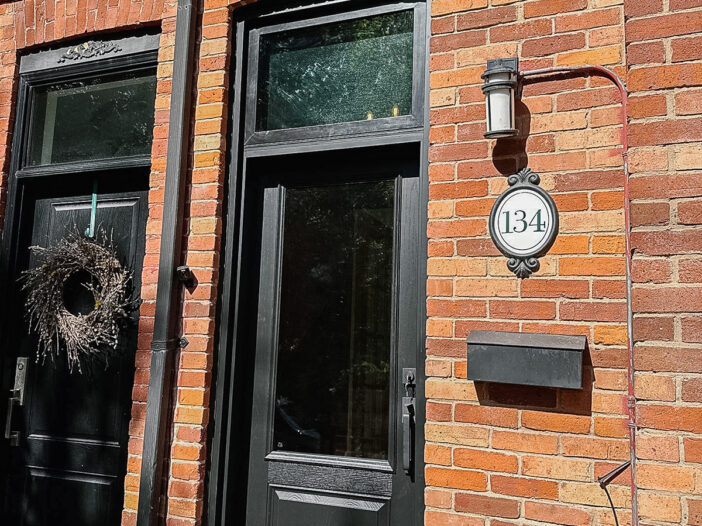 Black fiberglass front door in Toronto with large glass lite and operating transom above, featuring flat black hardware and a modern two-panel design installed on a residential home.