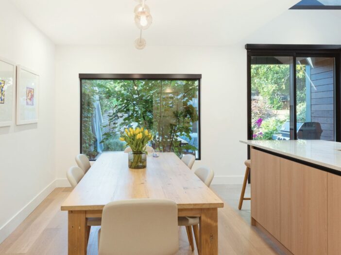 Wide shot of a modern living room featuring the newly-installed statement window framing the outdoor view.