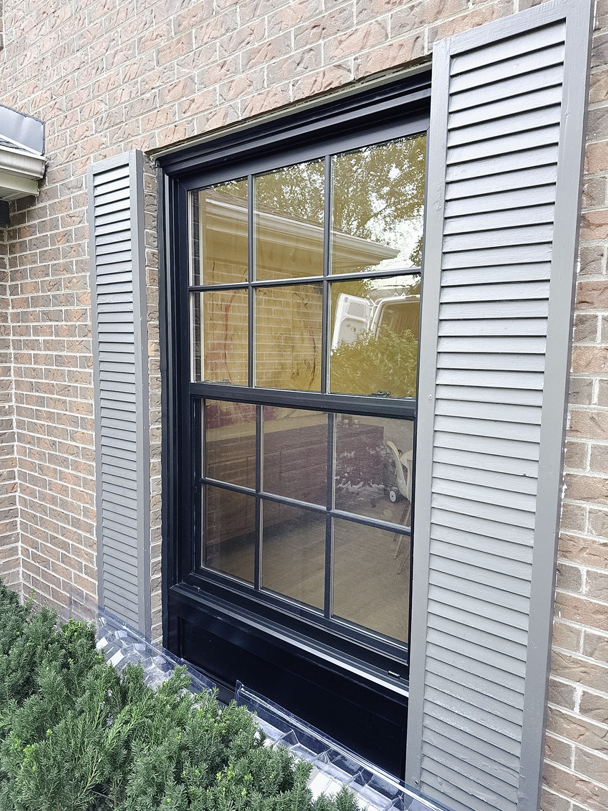 Close-up of black single hung vinyl window on home exterior.